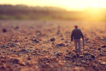 Surreales Bild eines mysteriösen Mannes, der während des Sonnenuntergangs allein auf dem Feld spaziert © tomertu
