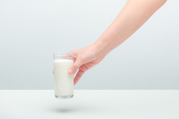 Young woman's hand taking a glass of milk from a table.