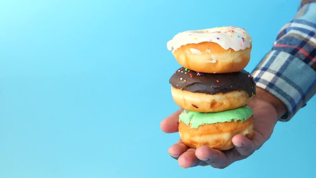  man's hand holding stack of fresh donuts close up 