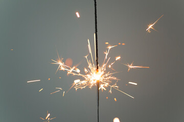 Sparkler lit burning down on a gray background 