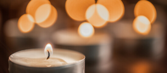 Many burning candles with light bokeh in backround. Candle flame close up