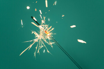 Sparkler lit burning down on a tidewater green color background