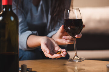 selective focus of alcoholic woman holding coins and glass of red wine