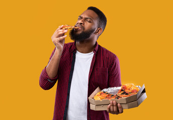 African American Man Enjoying Eating Pizza Standing Over Yellow Background
