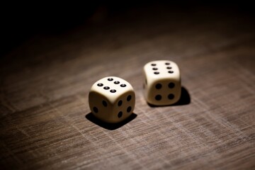 A close up dark portrait of two dice lying on a wooden table during a gamble. They both show all equal eyes after a role for a bet. Both sixes are at the top.