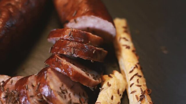 Sprinkle cumin on sliced sausage and bread. The tray rotates. Selective focus