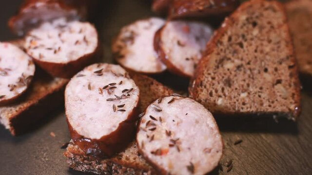Sprinkle cumin on sliced sausage and bread. The tray rotates. Selective focus