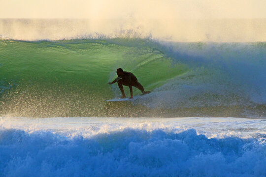 Surfer reitet eine gr&uuml;ne Welle in der goldenen Stunde vor Sonnenuntergang in Kapstadt S&uuml;dafrika