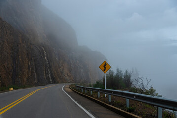 Traffic sign that indicates a curve in the part of a highway between slopes and cliffs. Boyaca. Colombia