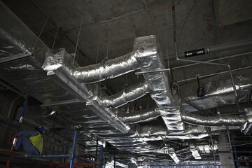 ducting work. duct Insulation. HVAC system in the construction site. Aluminum fabricated air flow duct. Technicians are assembling air duct for air conditioning and ventilation systems.