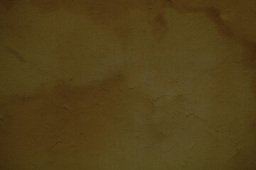 Weathered stained ochre wall background texture with rough plaster finish in close up in a full...