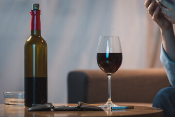 cropped view of alcohol-addicted woman near bottle and glass of red wine