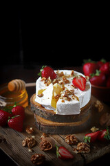 Selective focus. Camembert cheese with strawberries and honey. An exquisite wine appetizer. Healthy snack.