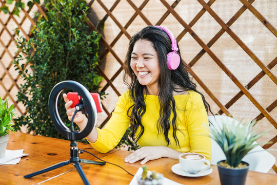 Young asian woman steaming live video online and have fun with technology - Influencer girl with headset, smartphone and led