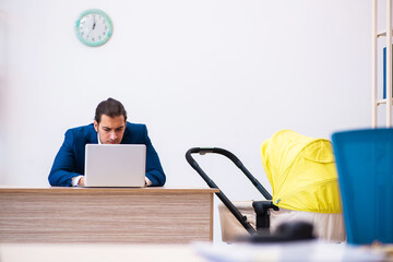 Young male employee looking after kid at workplace