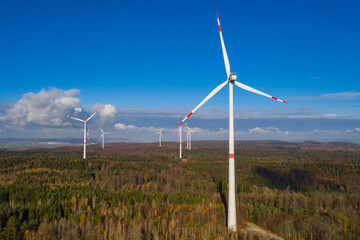 wind farm in a colorful autumn forest with blue sky