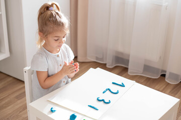 Naklejka premium Child preschooler making a numbers from plasticine. Home education.