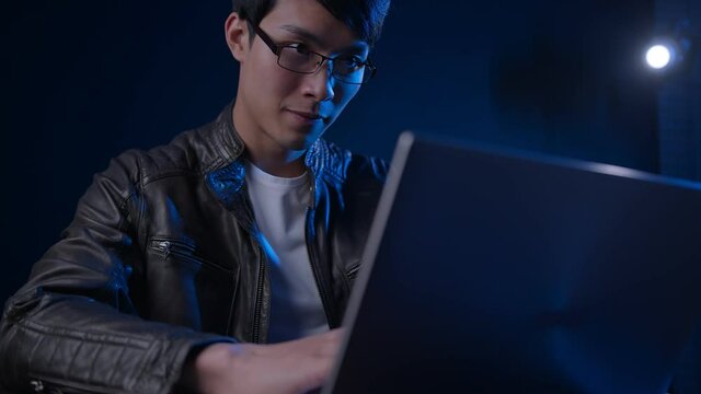 close up asian male programer working late with laptop night time with focus and concentrate studio shot dark background