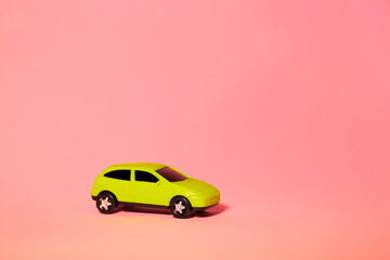 yellow toy car on pink background, concept idea of taxi and cargo delivery during quarantine