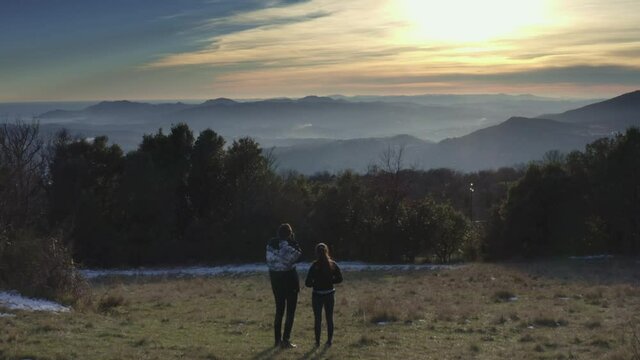 couple in the mountains contemplating sunset and taking pictures