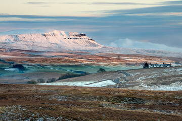Pen-y-ghent covered in snow with beautiful Winter evening sunlight. Yorkshire Dales National Park,...
