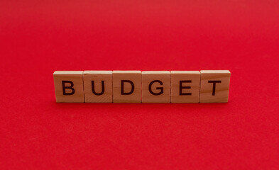 The inscription in wooden letters the word budget on a red background. Concept for business.