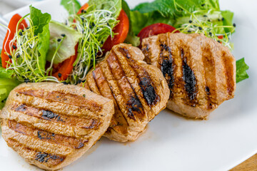 Meat with vegetables. Pork medallions. Grilled meat. Cutlets close-up. Beef.
