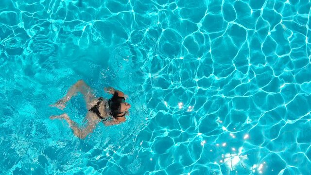 aerial view of young beautiful woman swimming breaststroke in the pool