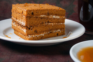honey cake with honey drips lies on a white plate