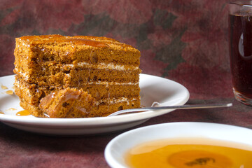 honey cake with honey drips lies on a white plate