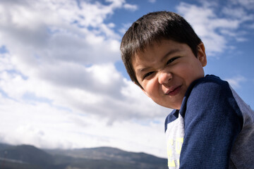 Cute little boy smiling against the blue sky