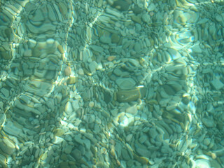 Pebbles visible in transparent water on the seabed