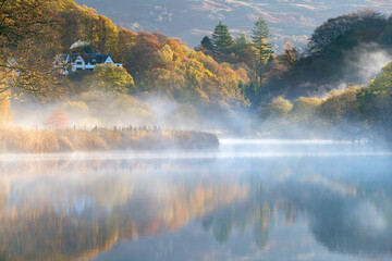 Beautiful autumn misty morning in the Langdale Valley, Lake District, with a quaint house and chimney smoking
