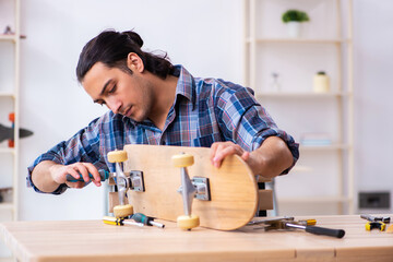 Young man repairing skateboard at workshop