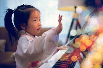 Asian toddler girl look up and learning piano lesson from online class during Covid-19 pandemic lockdown, e-learning, self isolation, new normal lifestyle, music education, early childhood activity