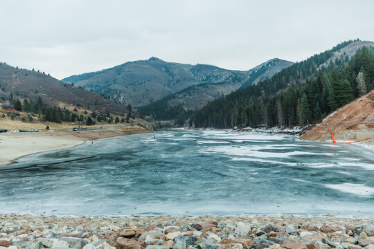 Tibble Fork Reservoir in Salt Lake City, Utah in the month of December. Mountains, trees and a frozen reservoir