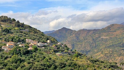 mountains, valleys, hills with vegetation and houses built on the hills, the sky with clouds