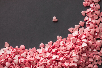 Pile of little pink heart shaped candies on the grey background. Free space for your Valentine's day greeting. Flat lay.
