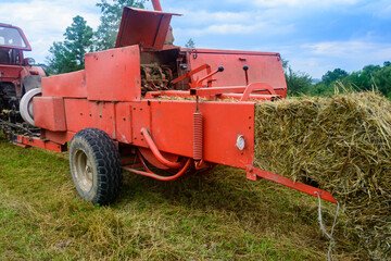 Old bale press, hay harvesting in the village for cattle, press work close up.