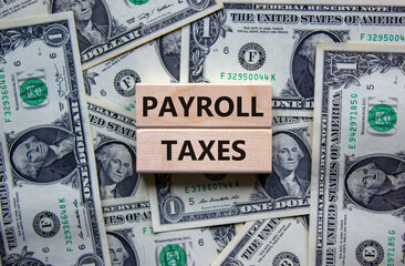 Payroll taxes symbol. Concept words 'Payroll taxes' on wooden blocks on a beautiful background from dollar bills. Business and payroll taxes concept.