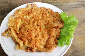 Traditional Thai style omelet with vegetable on white plate on wooden table. Food concept.