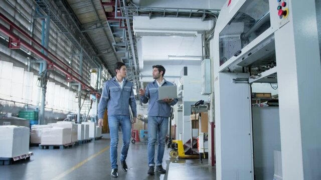 two engineer specialist professional in uniform walk and discuss consult inspecting working process in machinery factory background