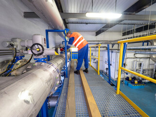 Worker checks the valves behind the compressors of the high-pressure biogas circuit - 403063255