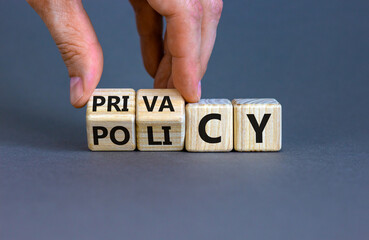 Privacy policy symbol. Hand turns the wooden cube with words 'Privacy policy' on a beautiful grey background. Business and privacy policy concept. Copy space.