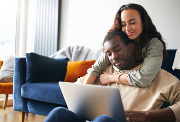 Relaxed Young Couple At Home Sitting On Sofa Browsing Internet On Laptop Computer