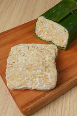 tempeh wrapped in banana leaves and tempeh slices on a wooden cutting board