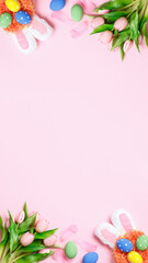 Easter eggs, tulips, bunny ears on a pink background. Greeting card with copy space flat lay.