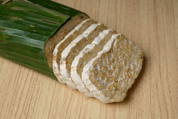 tempeh wrapped in banana leaves and tempeh slices on a wooden cutting board