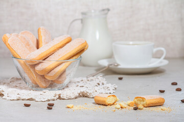 Italian savoiardi or ladyfingers biscuits on a plate and pieces of cookies on the table, a white...