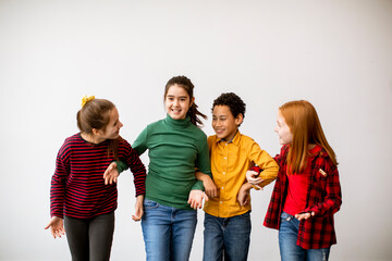 Portrait of cute little kids in jeans  talking and smiling, walking by white wall
